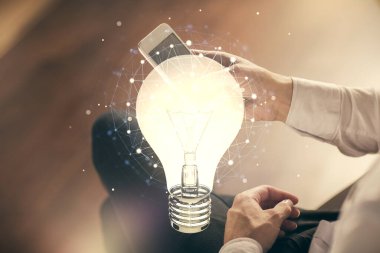 Dijital bir cihaz ve ampul hologram çizimi kullanarak erkeklerin ellerini tutarken çift pozlama. Fikir kavramı.