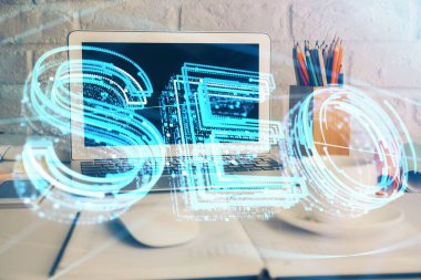 Bilgisayar ve seo çizim hologramı olan bir masanın çifte görüntüsü. Arama optimizasyon kavramı.