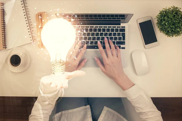 Doble exposición de las manos de las mujeres que trabajan en el dibujo del holograma de la computadora y la bombilla. Vista superior. Concepto de idea . — Foto de Stock