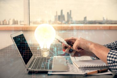 Dijital bir cihaz ve ampul hologram çizimi kullanarak insanın ellerini tutarken çift pozlama. Fikir kavramı.