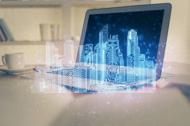 Ofisteki masaüstü bilgisayar geçmişi ve büyük kasaba binaları hologram çizimi. Çifte maruziyet. Akıllı şehir konsepti.