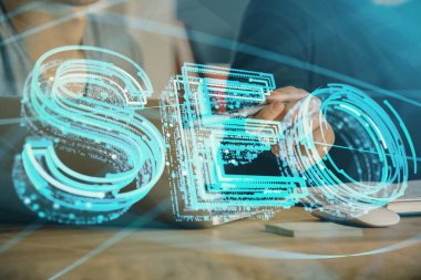 Arka planda bilgisayar üzerinde çalışan bir adamla birlikte çok sayıda simgeye maruz kalma. Arama motoru optimizasyonu kavramı.