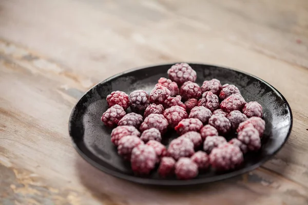 Frozen berries in bowls on wooden background. Selective focus.