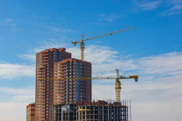 Mavi gökyüzüne karşı vinç ve inşaat alanı.