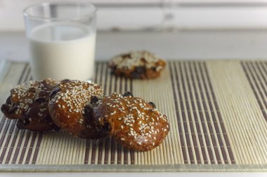 Bisküvi susam, Kuru üzüm ve bir bardak süt ile masada. Pencere pervazına üzerinde. Sağlıklı beslenme