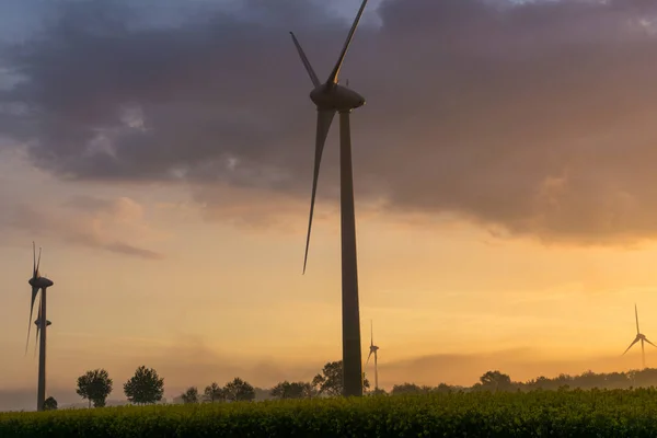 Windräder bei Sonnenaufgang und Nebel mit dunklen Wolken — Stockfoto