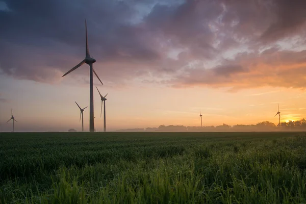 Windräder bei Sonnenaufgang und Nebel mit dunklen Wolken — Stockfoto