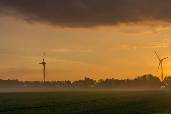 Windräder bei Sonnenaufgang und Nebel mit dunklen Wolken — Stockfoto