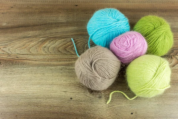 Bolas de lana de colores con agujas en una mesa de madera rústica — Foto de Stock