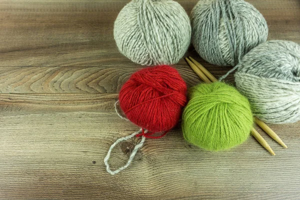 Bolas de lana de colores con agujas en una mesa de madera rústica — Foto de Stock
