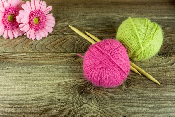 Boules de laine colorées avec aiguilles et une fleur sur une table en bois rustique — Photo