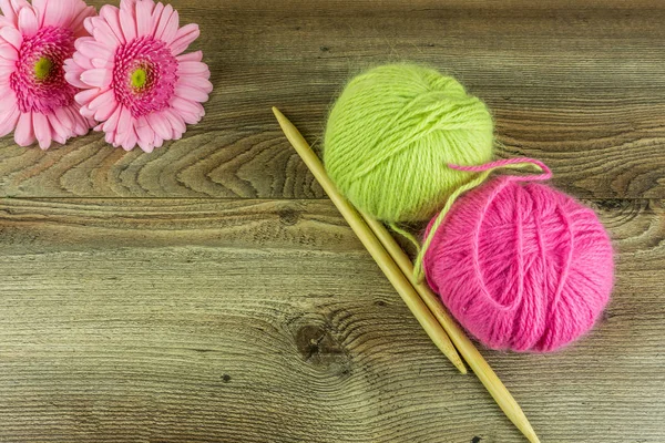 Bolas de lana de colores con agujas y una flor en una mesa de madera rústica — Foto de Stock