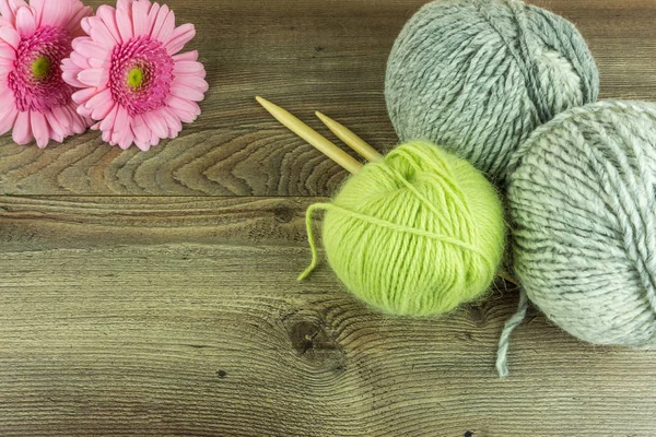 Boules de laine colorées avec aiguilles et une fleur sur une table en bois rustique — Photo