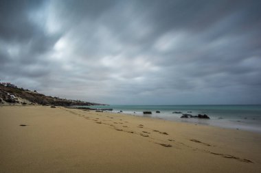 Koyu siyah bulutlar ile denizde plaj