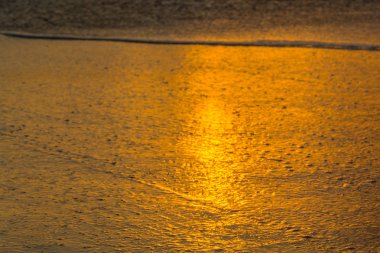 Gün batımında Atlantik Okyanusu üzerinde küçük dalgalar ile plaj