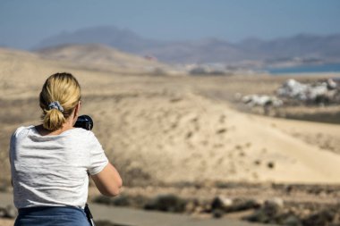Sarı saçlı kadın plaj ve alma fotoğraflar üzerinde duruyor