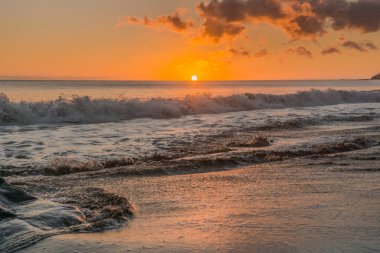 Sunset beach Fuerteventura lav kayaları, kara bulutlar ve küçük dalgalar ile