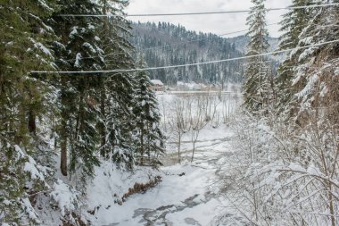 Karlı kış dağları ve donmuş karlı nehir