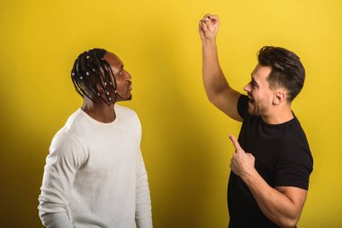 İki erkek, bir siyah erkek, bir Avrupalı, elinde hapları beyaz ve siyah tutuyor.