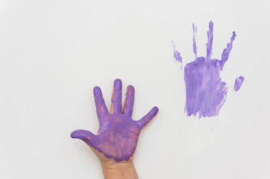 Beyaz arka planda yeşil, mavi ve mor renkte boyanmış çocuk elleri.
