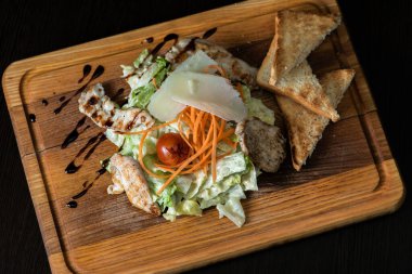 Tavuklu Yunan salatası, ahşap tepside domates.