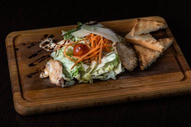 Tavuklu Yunan salatası, ahşap tepside domates.