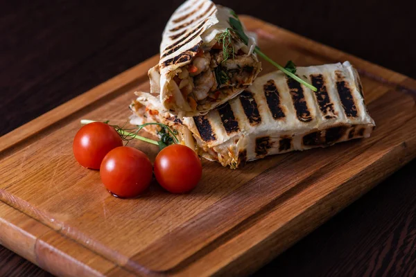 kebab in pita bread with meat and vegetables and tomatoes on a wooden tray