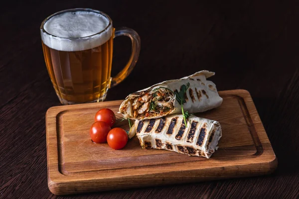 kebab in pita bread with meat and vegetables and tomatoes on a wooden tray