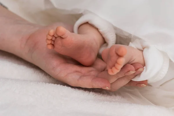 光の背景に生まれたばかりの赤ん坊の可愛くて小さな足 — ストック写真