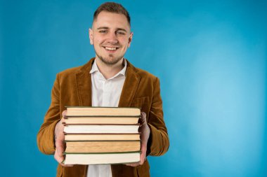 Genç iş adamı, Avrupalı iş adamı, iş adamı, takım elbiseli öğrenci mavi arka plan üzerine kitaplar tutuyor 