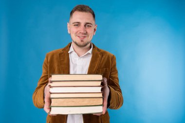 Genç iş adamı, Avrupalı iş adamı, iş adamı, takım elbiseli öğrenci mavi arka plan üzerine kitaplar tutuyor 