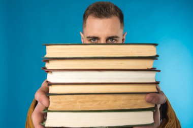 Genç iş adamı, Avrupalı iş adamı, iş adamı, takım elbiseli öğrenci mavi arka plan üzerine kitaplar tutuyor 