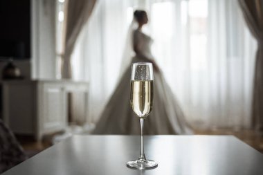 Genç bir kızın arka planında bir bardak köpüklü şampanya.