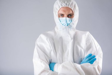 Koruyucu kıyafetli, yüzünde maske ve yüzünde korku olan mavi eldivenli bir virüs uzmanı ellerini kameraya doğru uzattığını gösteriyor. Salgın koronavirüs yüzünden sağlık sisteminin çökmesi.