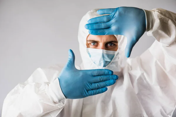 一位身穿防护服的病毒学家 戴着呼吸口罩 戴着蓝色手套 脸上带着恐惧 对着摄像机手举着谨慎的手 流感大流行导致医疗系统瘫痪 — 图库照片