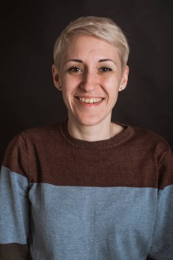 Duygusal genç, güzel, mavi kot pantolon giyen ve gri arka planda oturan seksi kızın portresi.