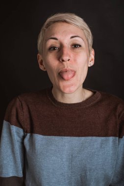 Duygusal genç, güzel, mavi kot pantolon giyen ve gri arka planda oturan seksi kızın portresi.