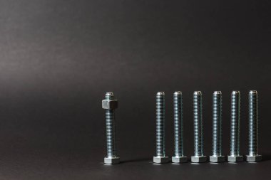 Bir satır arka planda metal cıvata ve somunlar. Krom vida cıvata ve somun izole. Çelik cıvata ve somun deseni. Somun ve cıvata seti. İş için araçlar. Siyah beyaz