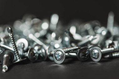 Galvanize vidalar, yarım daire şeklinde bir kafa, haç şeklinde bir delik ve karanlık bir arka planda bir çamaşır makinesi. Kapat.