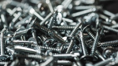 Galvanize vidalar, yarım daire şeklinde bir kafa, haç şeklinde bir delik ve karanlık bir arka planda bir çamaşır makinesi. Kapat.