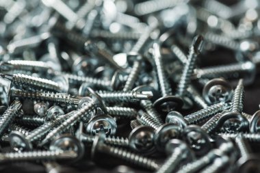 Galvanize vidalar, yarım daire şeklinde bir kafa, haç şeklinde bir delik ve karanlık bir arka planda bir çamaşır makinesi. Kapat.