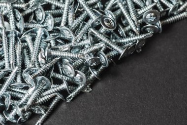 Galvanize vidalar, yarım daire şeklinde bir kafa, haç şeklinde bir delik ve karanlık bir arka planda bir çamaşır makinesi. Kapat.