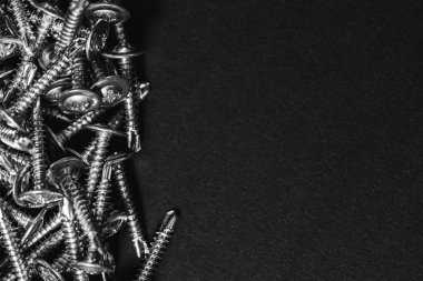 Galvanize vidalar, yarım daire şeklinde bir kafa, haç şeklinde bir delik ve karanlık bir arka planda bir çamaşır makinesi. Kapat.