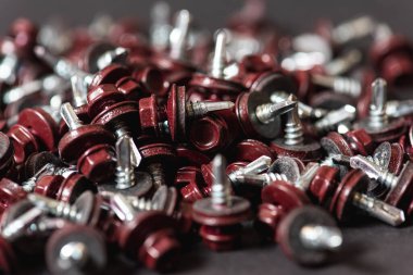 Çatı vidalarının üst görünümü arka plan dokusunu bozar. Kırmızı çatı vidaları arka planda. Çatıyı kızıl saçlılarla onarmak için kendi kendine dokunan vidalar.