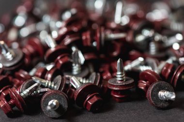 Çatı vidalarının üst görünümü arka plan dokusunu bozar. Kırmızı çatı vidaları arka planda. Çatıyı kızıl saçlılarla onarmak için kendi kendine dokunan vidalar.