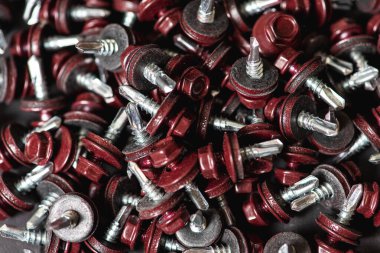 Çatı vidalarının üst görünümü arka plan dokusunu bozar. Kırmızı çatı vidaları arka planda. Çatıyı kızıl saçlılarla onarmak için kendi kendine dokunan vidalar.