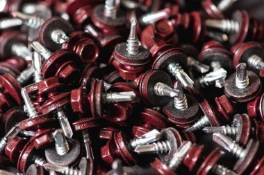 Çatı vidalarının üst görünümü arka plan dokusunu bozar. Kırmızı çatı vidaları arka planda. Çatıyı kızıl saçlılarla onarmak için kendi kendine dokunan vidalar.