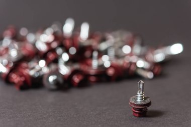 Çatı vidalarının üst görünümü arka plan dokusunu bozar. Kırmızı çatı vidaları arka planda. Çatıyı kızıl saçlılarla onarmak için kendi kendine dokunan vidalar.