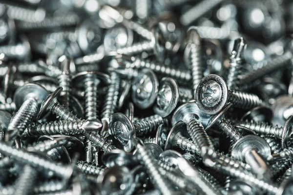 Galvanize vidalar, yarım daire şeklinde bir kafa, haç şeklinde bir delik ve karanlık bir arka planda bir çamaşır makinesi. Kapat.