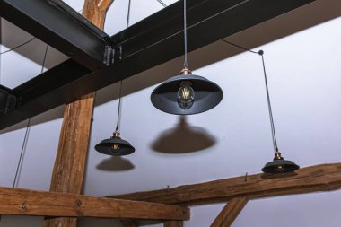 Oda içi, ahşap kirişler ve karanlık lambalar.